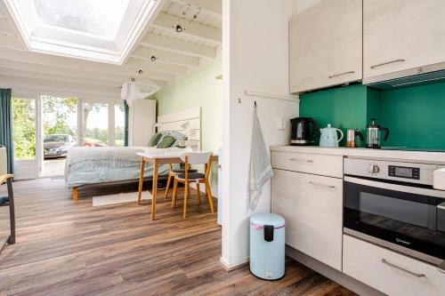 a kitchen and living room with a bed and a table at Light tiny house in green area with sauna option in Stoutenburg