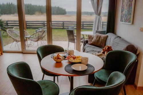 a table and chairs in a living room with a table and a window at Osada pod Gwiazdami & SPA - FAMILY ogrodzony dom, prywatne JACUZZI, kominek, grill, ognisko, Kajaki, Plaża, Jeziora in Łasko