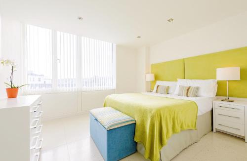 a white bedroom with a large bed with a yellow blanket at 28 Rocklands in Newquay in Newquay
