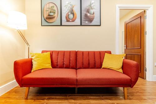 a red couch with yellow pillows in a living room at Cozy Modern Flat Walsall Town Centre with Wi-Fi in Walsall