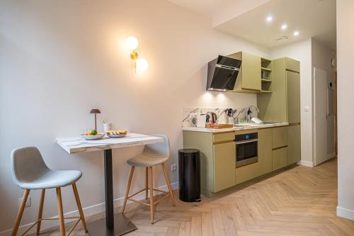 une cuisine avec des placards verts, une table et des tabourets dans l'établissement OIQIA • Palace Hôtel • N°3, à Tours