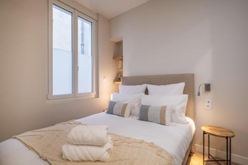 une chambre avec un lit avec des oreillers blancs et une fenêtre dans l'établissement OIQIA • Palace Hôtel • N°3, à Tours