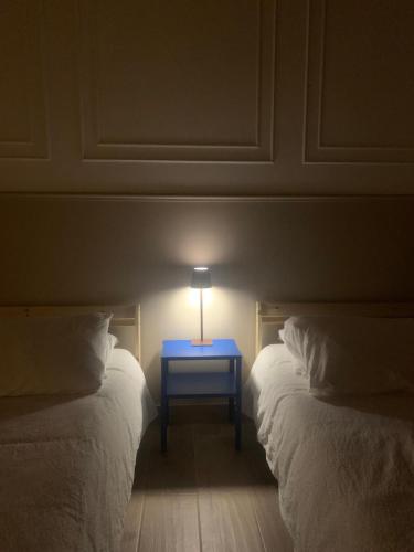 a blue nightstand sitting between two beds in a room at CENTER'S ROOMS GARLASCO City Haven in Garlasco