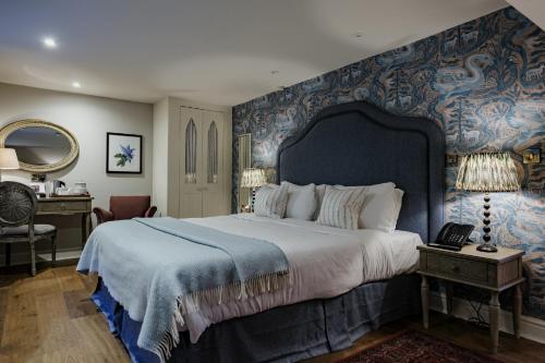 a bedroom with a large bed with a blue wall at The Manor House Hotel in Moreton in Marsh