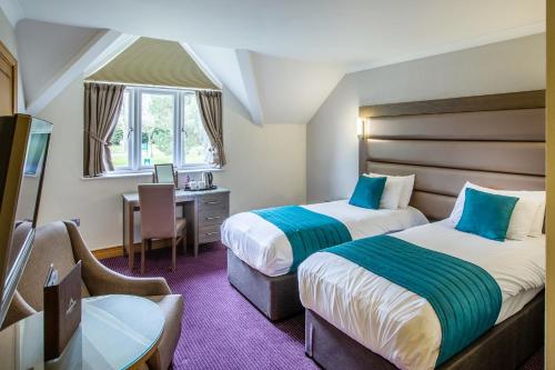 a hotel room with two beds and a desk at Ardencote in Henley in Arden
