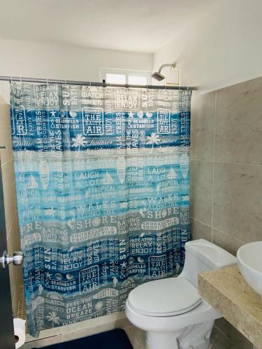 a bathroom with a toilet and a blue shower curtain at Depa en Cancun con alberca in Cancún
