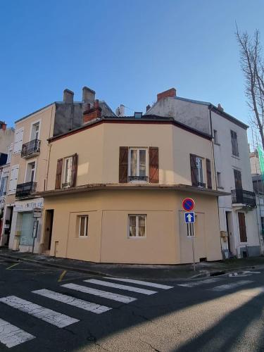 un bâtiment jaune au coin d'une rue dans l'établissement La Savane de VICHY - 4 min GARE, à Vichy