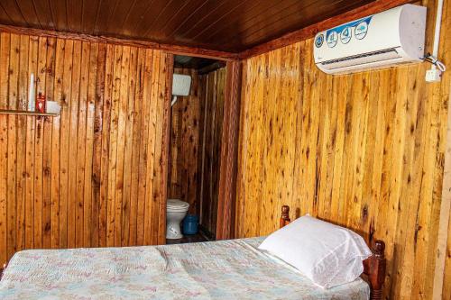 a bedroom with wooden walls and a bed with a air conditioner at Rincón Coratei in Coratei