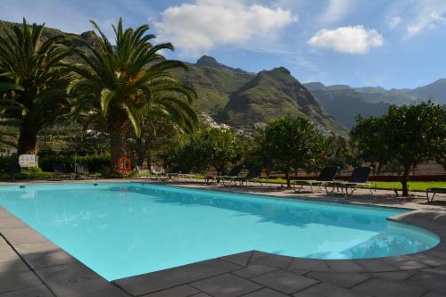a pool with palm trees and mountains in the background at Hotel Rural Las Longueras in Agaete