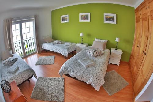 a bedroom with two beds and green walls at Liv In by Ericeira Property in Santo Isidoro