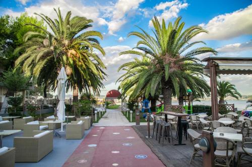 a restaurant with palm trees and tables and chairs at Ignatia Hotel in Nafplio