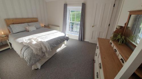 a bedroom with a bed and a dresser and a window at Whitehill Cottage in Castlewellan