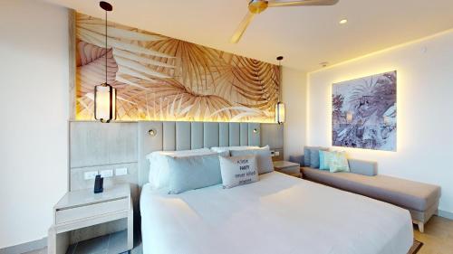 a bedroom with a large white bed and a couch at Royalton CHIC Antigua, An Autograph Collection All-Inclusive Resort - Adults Only in Saint Johnʼs