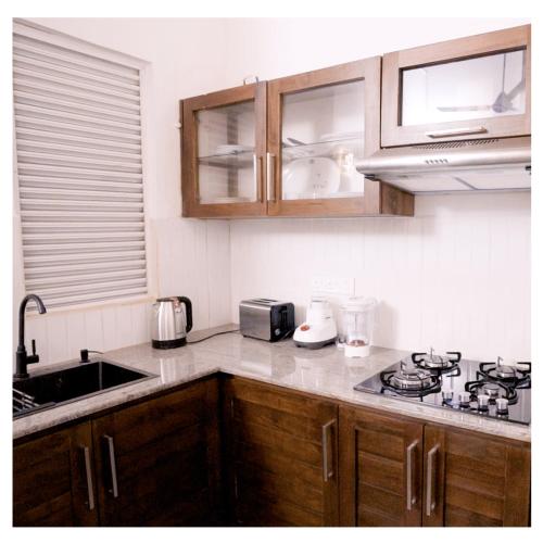 a kitchen with wooden cabinets and a counter top at Diyawanna Villa - Deluxe Double Room in Colombo in Sri Jayewardenepura Kotte