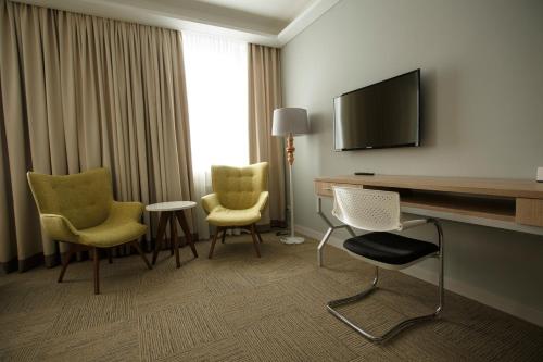 a hotel room with a desk and chairs and a television at GREEN Which Hotel in Petropavlovsk