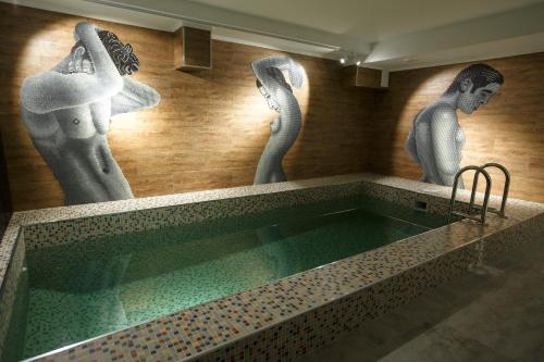 uma piscina com estátuas de mulheres na parede em GREEN Which Hotel em Petropavl