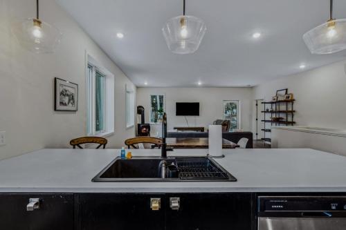 a kitchen with a sink and a living room at Fireplace Woods Club Access - Modern Quechee in Quechee