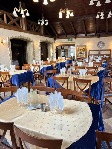 a dining room with white tables and blue chairs at Hotel Amalia in Smokovce