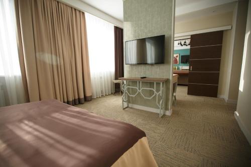 a hotel room with a bed and a flat screen tv at GREEN Which Hotel in Petropavlovsk