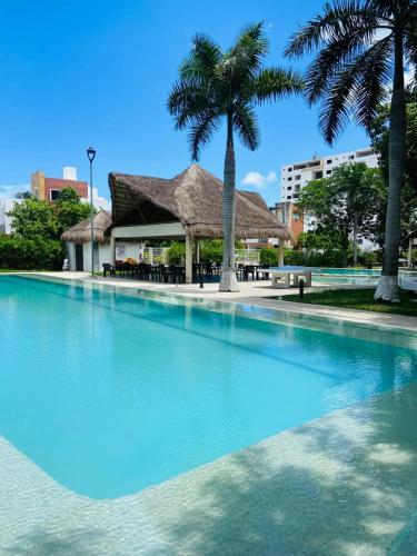a swimming pool with palm trees and a building at Depa en Cancun con alberca in Cancún