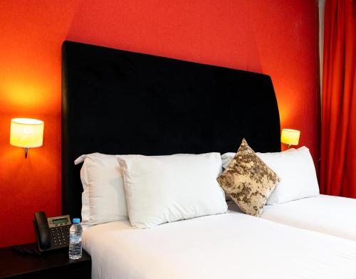 a bedroom with two beds and a red wall at The Fourteen Luxury Boutique Hotel in Casablanca