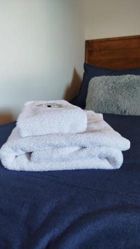 a pile of white towels sitting on a bed at Complejo Puente viejo JMT in Trevelín