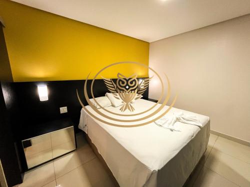 a bedroom with a bed with a yellow wall at Coruja Imob - Flat Crystal Place in Goiânia