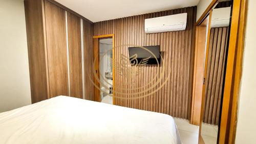 a bedroom with a white bed and a wooden wall at Coruja Imob - Flat Crystal Place in Goiânia