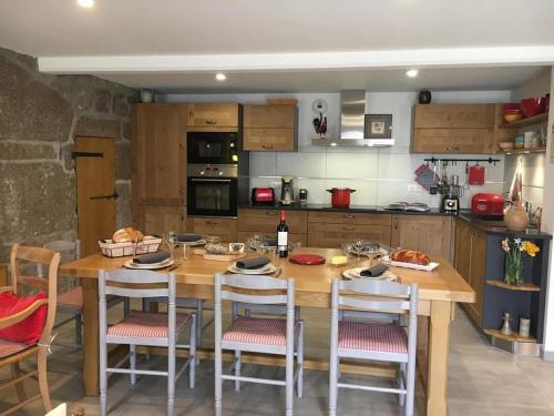 une cuisine avec une table en bois et quelques chaises dans l'établissement Gite la parro, à Malbouzon