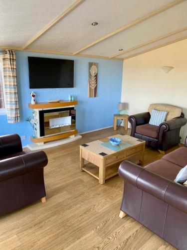 a living room with two couches and a tv at Limestone Lodges in Bothel