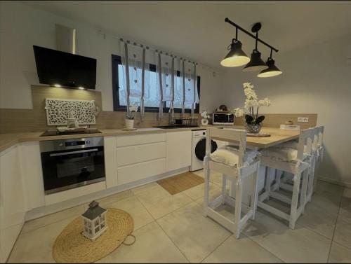 une cuisine avec des armoires blanches et une table avec des chaises dans l'établissement Dépendance de charme, à Ruaudin