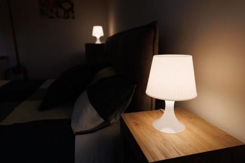 a white lamp on a table next to a bed at Casa Nicole Elegante Monolocale a Collegno in Regina Margherita