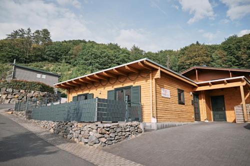 a log cabin with a stone wall in front of it at Ferienhaus Nina am Riedener Waldsee in Rieden