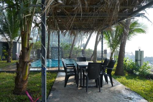 a table and chairs under a pavilion with palm trees at Sea Facing Luxurious Private Pool Villa in Alibag
