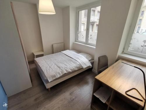 a bedroom with a bed and a table and two windows at Chambre chez l'habitant- Saint-Étienne, France in Saint-Étienne