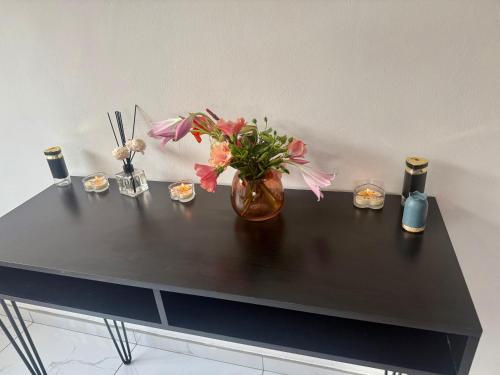 a black table with a vase with flowers and candles at Horizon Bed and Breakfast in Roodepoort
