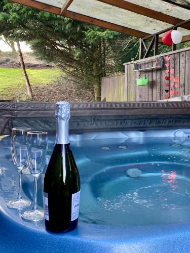 a bottle of wine and glasses on a table next to a swimming pool at Limestone Lodges in Bothel