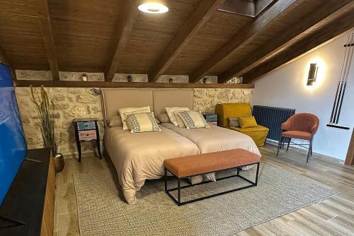 a bedroom with a large bed and a chair at Casa Vieja de la Abuela in Fuentesaúco de Fuentidueña