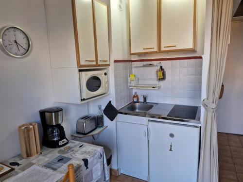 une petite cuisine avec un évier et un micro-ondes dans l'établissement studio belle vue, à La Londe-les-Maures