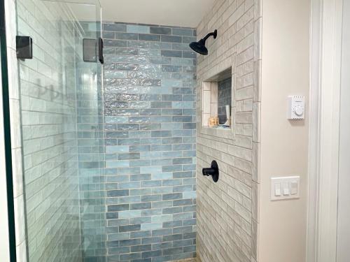 a bathroom with a shower with blue tiles at Puget Sound Chic Romantic Cottage with Private Beach Access & Gated Entry in Port Ludlow