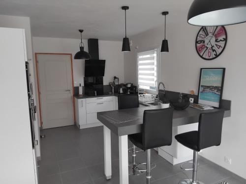 une cuisine avec une table et des chaises et une horloge au mur dans l'établissement Maison 130 m2 4 chambres, à Landaul
