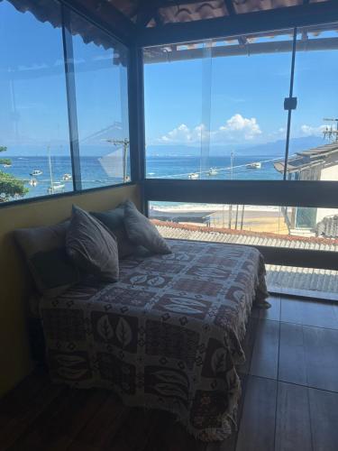 a bedroom with a bed with a view of the ocean at Suítes Pouso do Sol in Praia de Araçatiba