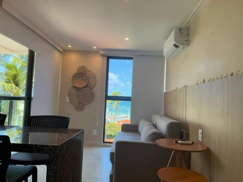 a living room with a couch and a table at Flat pé na areia na praia de Porto de Galinhas próximo as piscinas naturais. in Porto De Galinhas