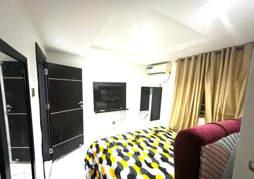 a bedroom with a bed and a tv on the wall at KOLS Apartment in Lagos