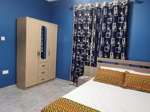 a bedroom with a bed and a cabinet and a curtain at Tropical Oasis in Accra - 2 Bedroom Apartment in Accra
