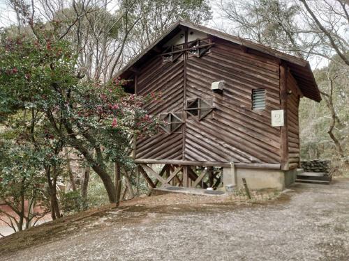 a small wooden building with a tree and flowers at Miroku Nature Park Campsite - Vacation STAY 45970v in Sanuki