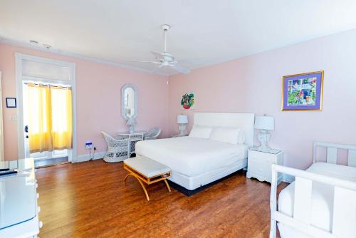 Un dormitorio con una cama blanca y suelo de madera. en King Suite at Curry Mansion with Heated Pool!, en Key West