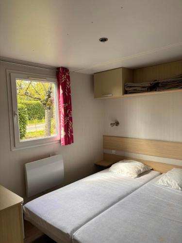 deux lits dans une petite pièce avec une fenêtre dans l'établissement Le Camping de Ripan, à Bessenay