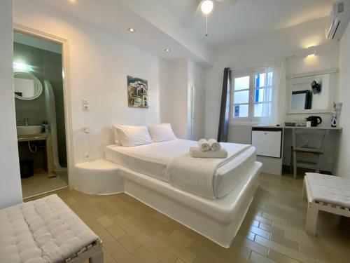 a white bedroom with a large bed and a bathroom at Serene Hill in Naousa