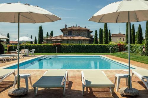 une piscine avec deux chaises et deux parasols dans l'établissement La Pergola, à Lucignano